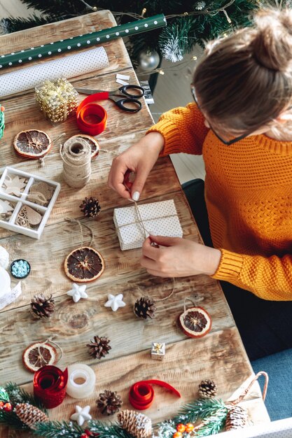 Young woman wrapping christmas present on table