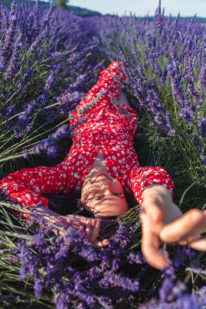 A young woman in a wreath on her head lies on a lavender field