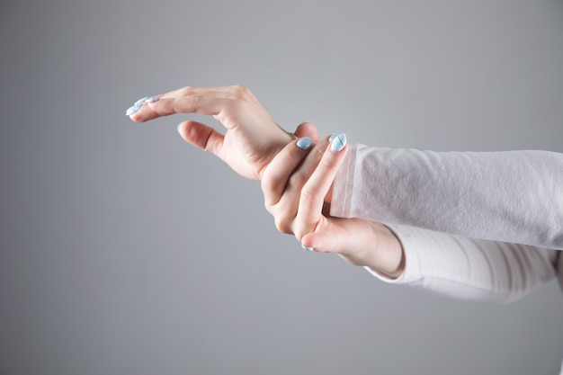 Photo in a young woman, wrists hurt on a gray scene