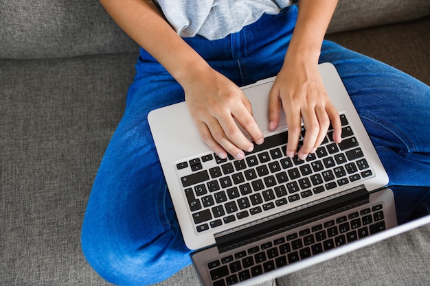 Foto giovane donna che scrive sul computer sul divano