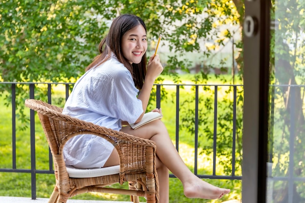 Young woman writing notebook at balcony.