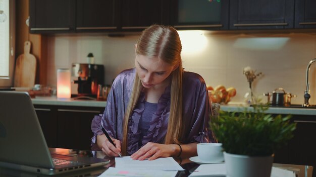 若い女性が自宅のテーブルに紙を書いています