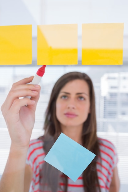 Young woman writing on sticky note