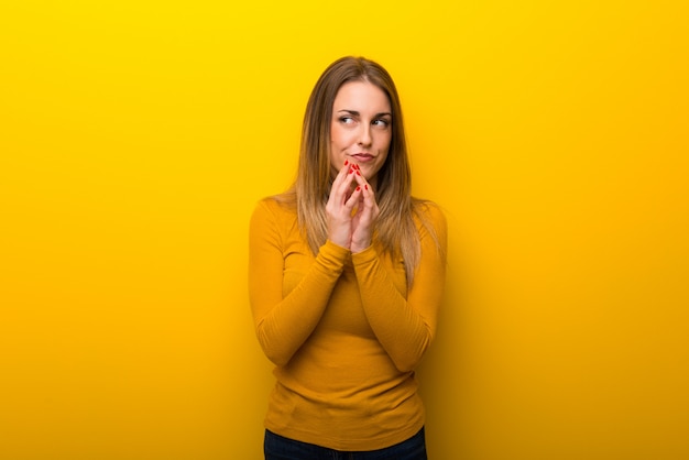 Young woman on yellow background scheming something