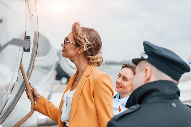 Photo a young woman in yellow clothes is accompanied by an airline workers