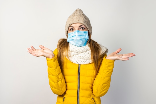 Foto giovane donna in una giacca gialla e un cappello con una mascherina medica