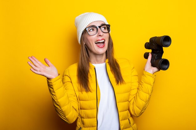 Young woman in yellow jacket holding binoculars