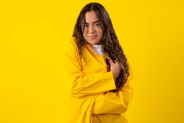 Young woman a yellow raincoat on a yellow background