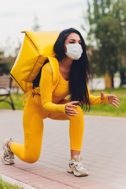 Young woman in yellow shirt delivering food using gadgets to track order at the city's street courier using online app for receiving payment and tracking shipping address modern technologies