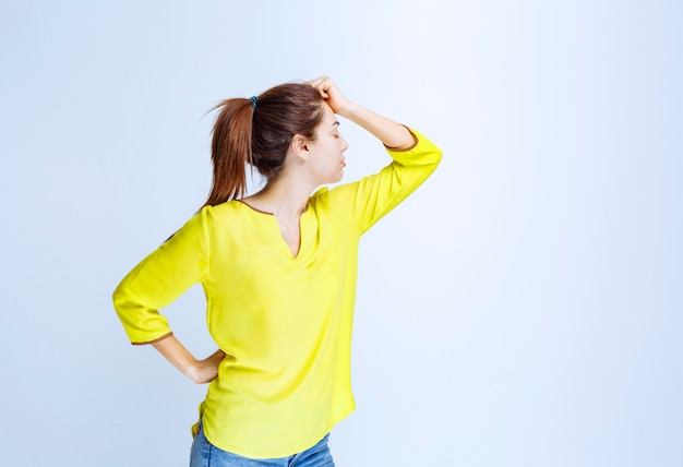 Young woman in yellow shirt looks tired and sleepy