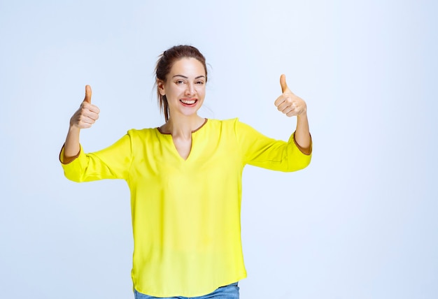 Young woman in yellow shirt showing thumb up