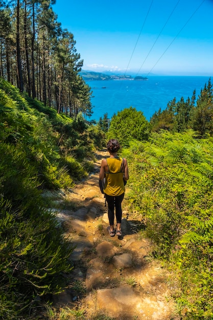 A young woman in a yellow shirt on the trail going down to the town of Orio Guipuzcoa Basque Country