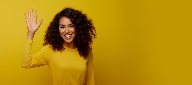 Young woman in yellow shirt with her arm up in the air on yellow background