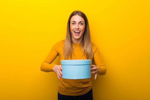 Young woman on yellow  surprised because has been given a gift