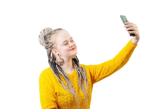 Молодая женщина в желтом свитере со смартфоном на белом фоне