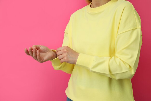 Young woman in yellow sweatshirt against pink surface