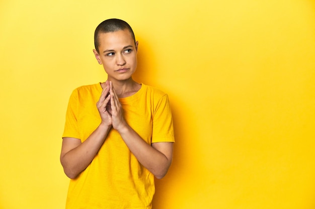 Young woman in yellow tee yellow studio backdrop making up plan in mind setting up an idea