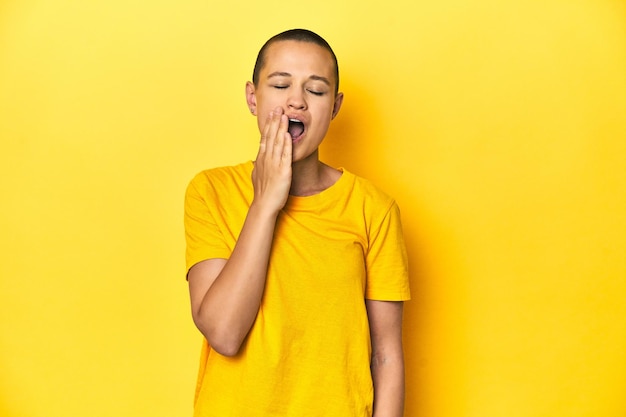 Photo young woman in yellow tee yellow studio backdrop yawning showing a tired gesture