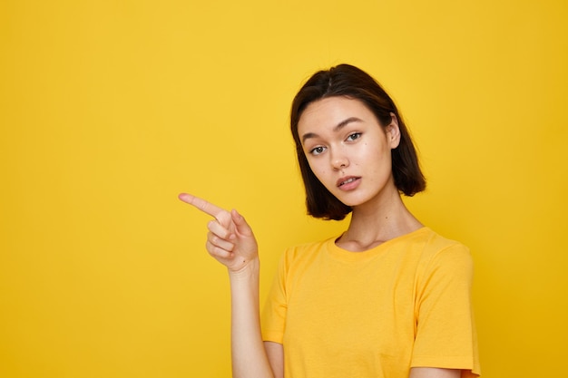 Young woman in yellow tshirt posing fashion yellow background