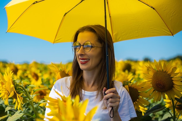 Young woman under yellow umbrella at sunflower field