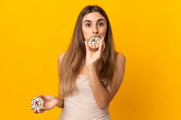 Photo young woman over yellow wall holding a donut