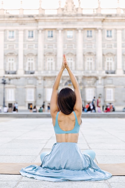 Giovane donna yoga all'aperto in un parco al tramonto vicino al palazzo reale di madrid