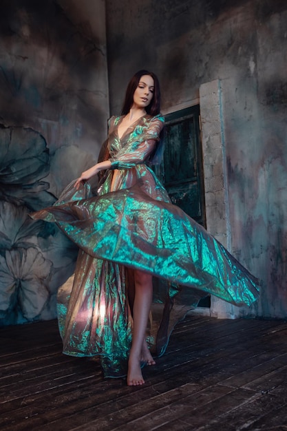 Young women are brunette spinning and dancing in a dark gloomy room the dress fluttering on the fly Art photo A woman looks like a sad little mermaid from a fairy tale