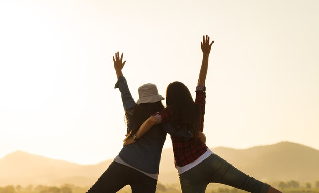 Le giovani donne si divertono con le braccia alzate insieme davanti alla montagna durante il tramonto felicità successo amicizia e concetti comunitari community