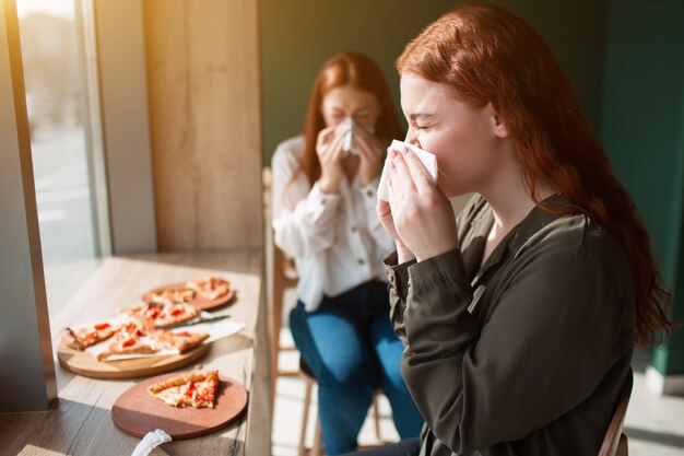 Young women blow nose in a napkin