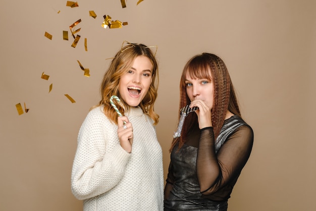 Young women blowing a festive tune and holding a candy cane