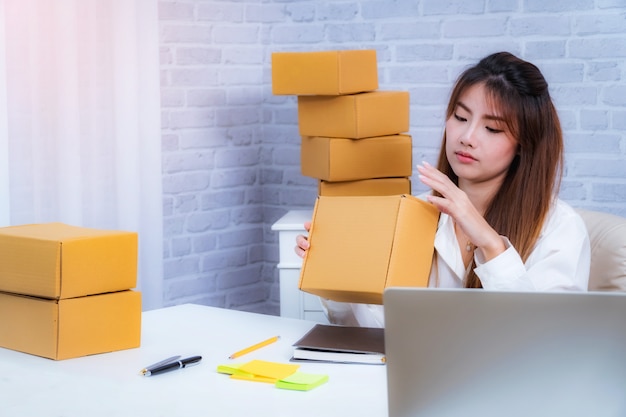 Foto imprenditore delle giovani donne che lavora a casa l'imballaggio dell'ufficio su fondo