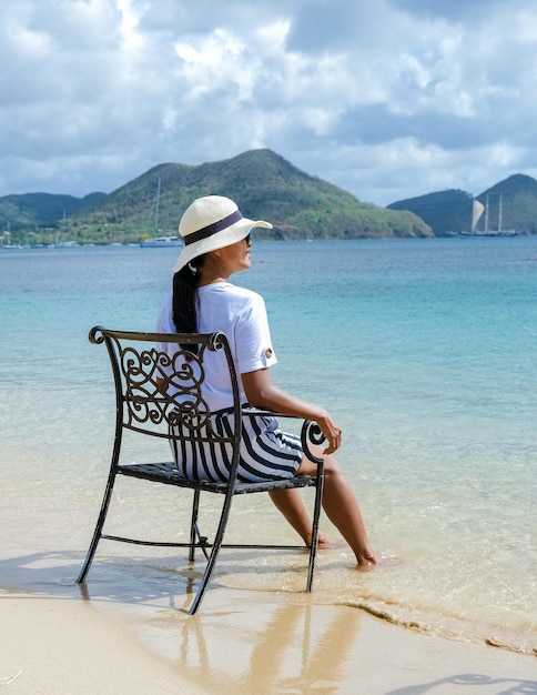 Young women on a chair with the feet in the ocean watching the\
beautiful caribbean ocean of st lucia