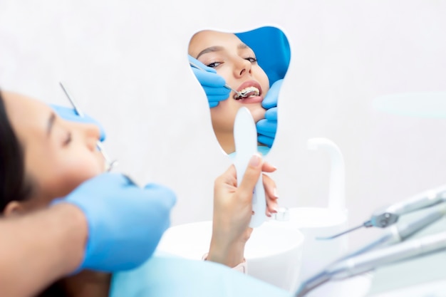 Young women checks her teeth in the mirror. New dental implants.