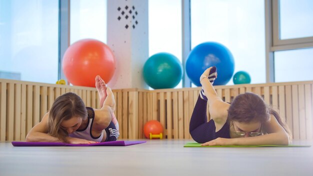 Young women doing fitness in the studio Training their leg stretching lying on their stomach