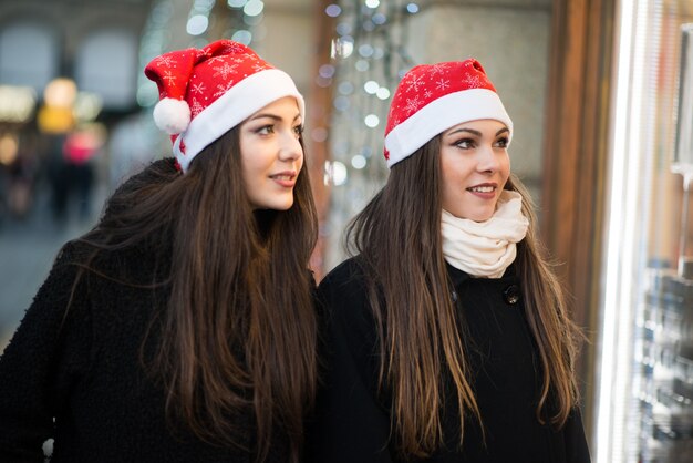 Молодые женщины друзья делают покупки вместе перед Рождеством