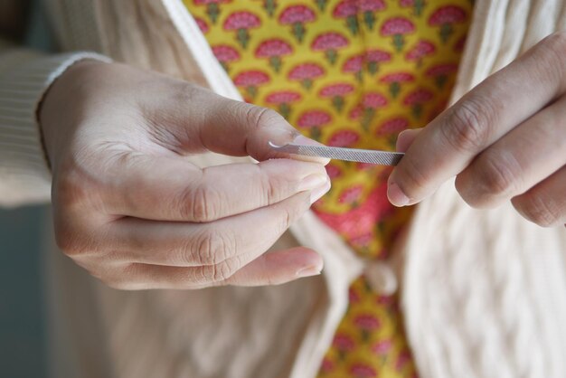 若い女性の手で指の爪を切る