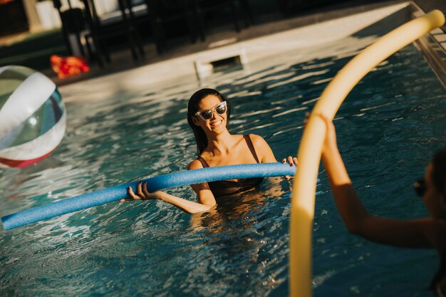 Young women having fun  with swimming pool noodles