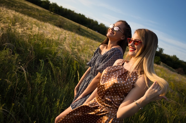 Young women holding hands on the field. Summer sunset sun.