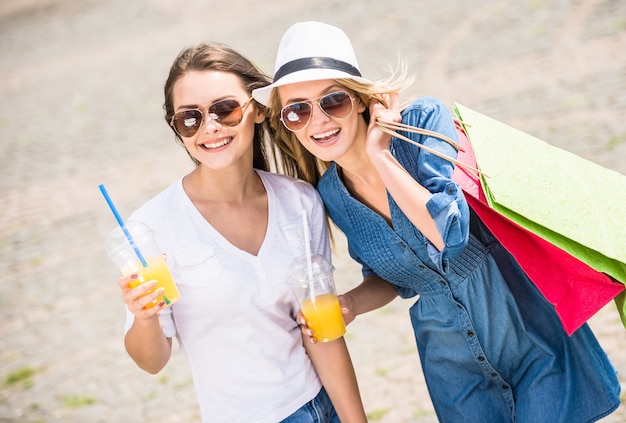 Foto giovani donne che tengono i sacchetti della spesa e vetri di succo.