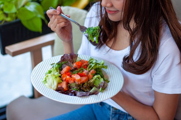 Foto le giovani donne che intendono perdere peso stanno mangiando un'insalata di verdure al salmone per una buona salute. donne che scelgono il concetto di dieta alimentare sana