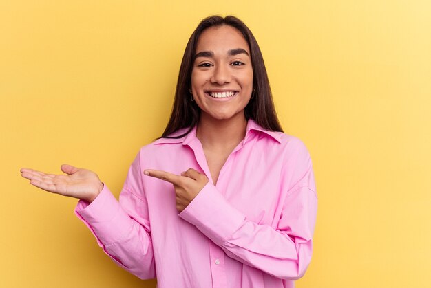 Young women isolated excited holding a copy space on palm.