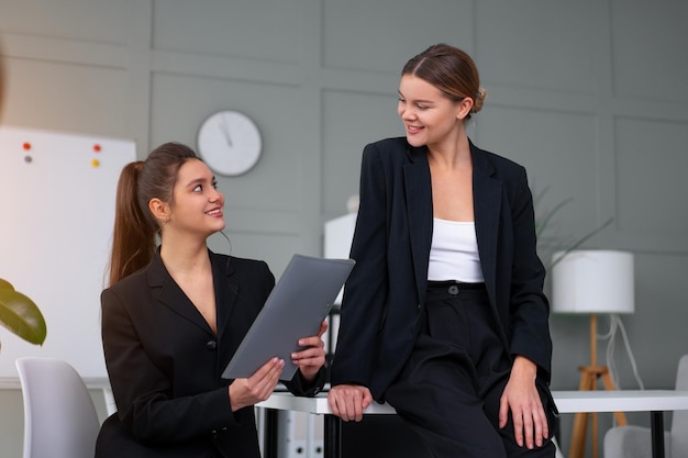 Young women leaders are checking financial statements from paper documents Two female confident business worker dressed black suit in office checking financial document