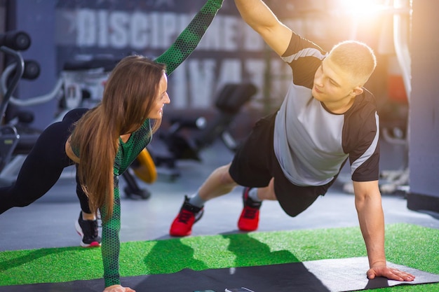 Young women and man go in for sports at gym Two athletes are stretching look at each other give five