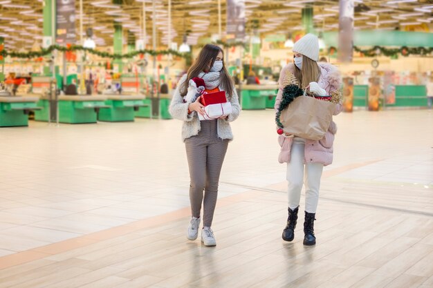 モールでクリスマスの医療マスクショッピングの若い女性。