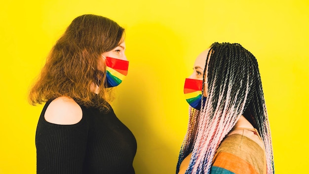 Young women in protective rainbow mask Side view of two females standing opposite each other in mask lgbt