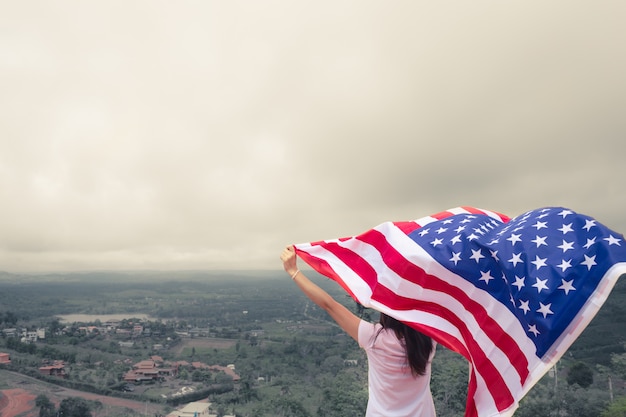 Le giovani donne alzano la bandiera americana nazionale contro il cielo blu. festa dell'indipendenza, 4 luglio Foto Premium