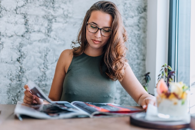 Young women reading magazine on her lunch break in coffee shop.