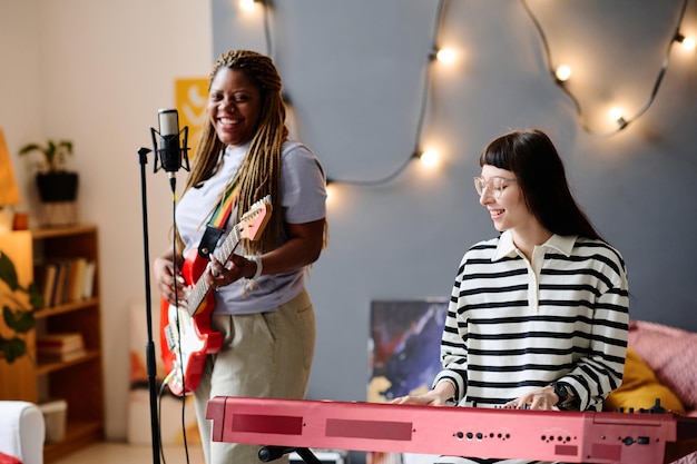 Young women rehearsing their performance in studio they singing song and playing guitar and piano