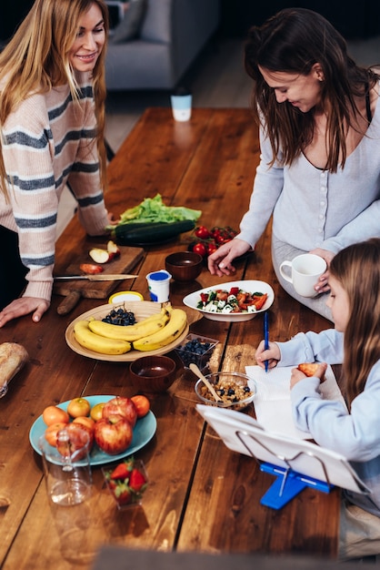 Young women set the table, girl does her homework.