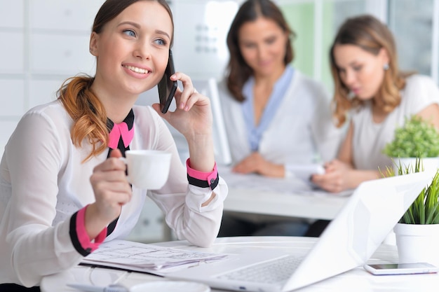 Young women sit at the table and work in a modern office